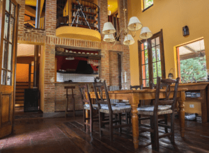 Rustic dining room with high ceiling, brick walls and mahogany coloured hardwood flooring