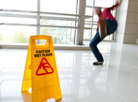 Man slipping over and a wet floor sign.