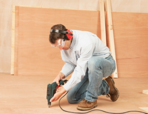 Tradesman installing plywood onto a floor.