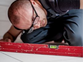 Man checking the subfloor with a two metre long spirit level.