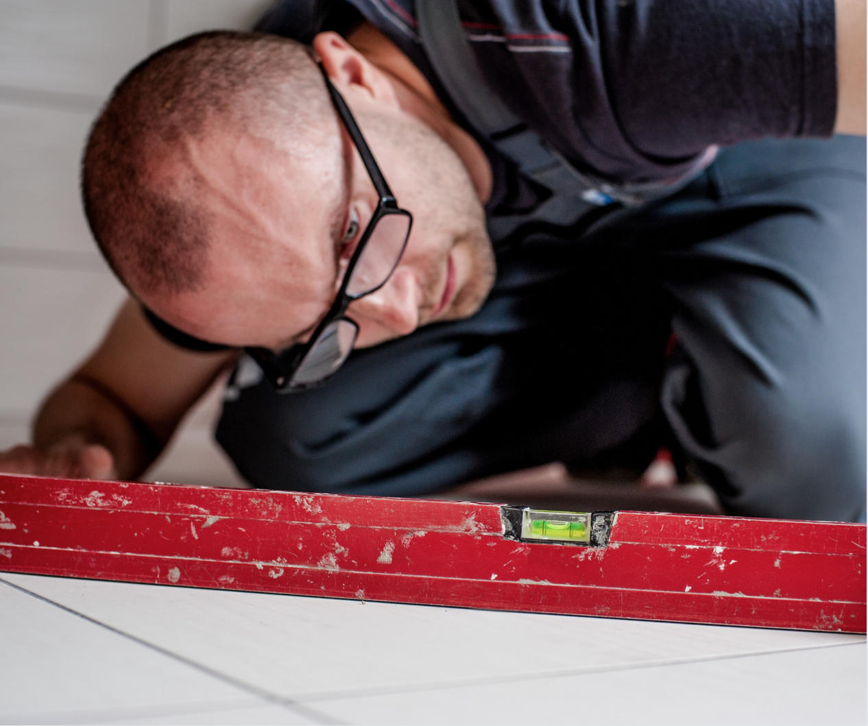 Man checking the subfloor with a two metre long spirit level.